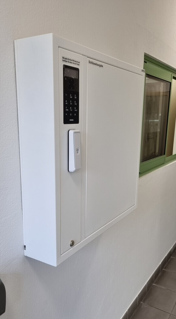 Weißer, elektronischer Schlüsselschrank an der Wand mit PIN-Tastatur und RFID-Leser zur sicheren Schlüsselverwaltung
