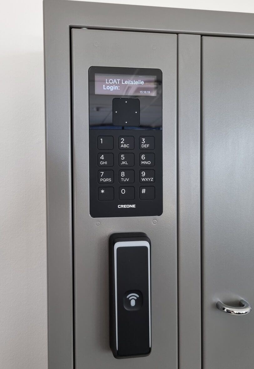 Metallschrank mit elektronischem Zahlencode-Tastenfeld und RFID-Lesegerät, Display zeigt Login-Maske an