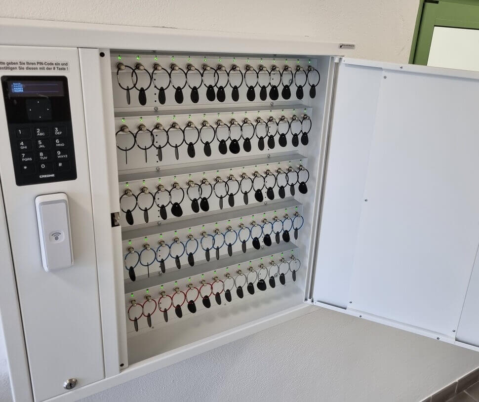 Elektronischer Schlüsselschrank, geöffnet, mit vielen Schlüsseln an nummerierten Haken und digitalem Bedienfeld