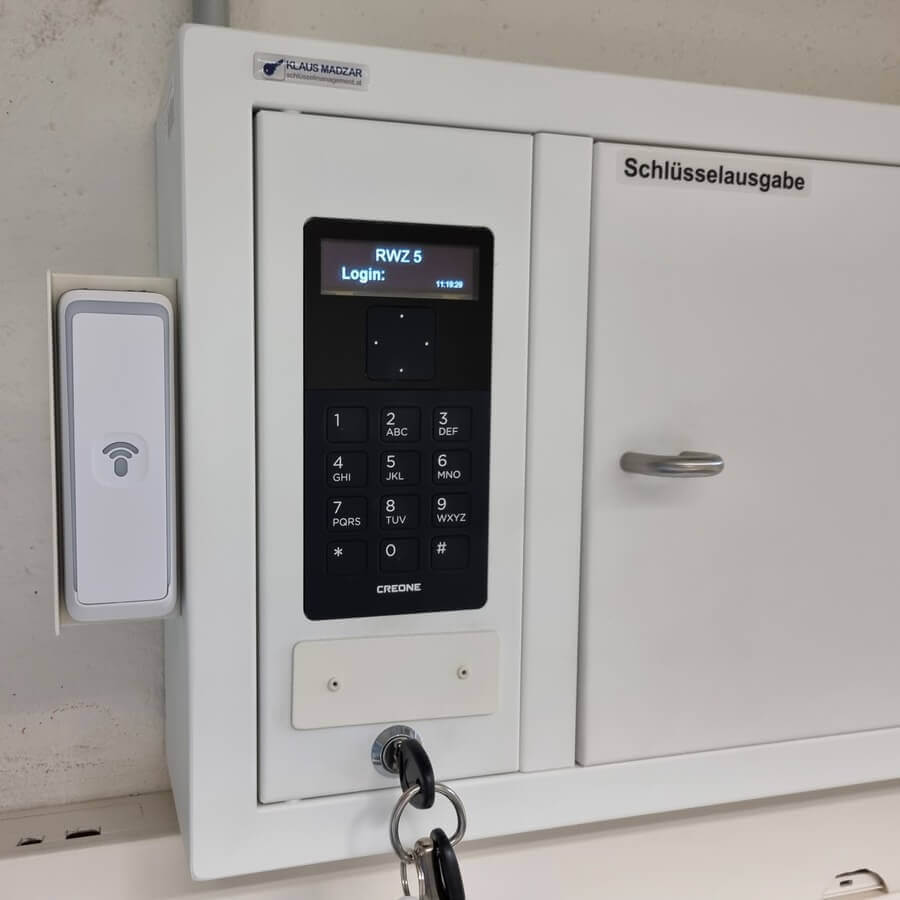 Weißer Schlüsselausgabeschrank mit elektronischem Zahlenschloss, Transponderleser und angehängtem Schlüsselbund