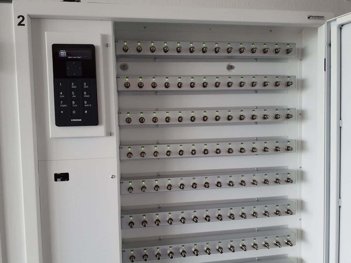 Offener elektronischer Schlüsselschrank mit zahlreichen beschrifteten Schlüsselplätzen und integriertem Bedienfeld zur Zugangskontrolle