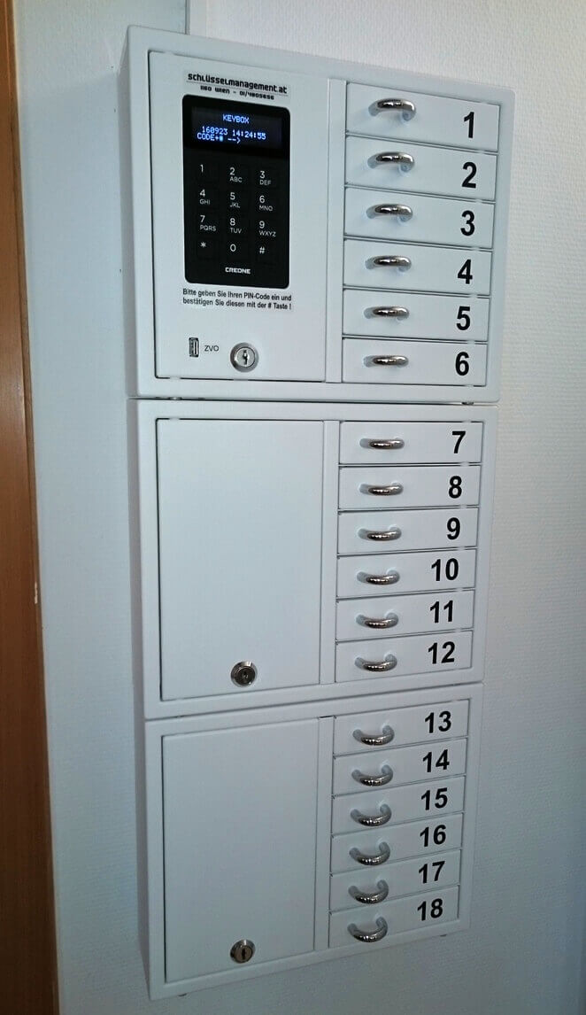 Weißer, elektronischer Schlüsselschrank mit 18 nummerierten Fächern und digitalem PIN-Tastaturfeld