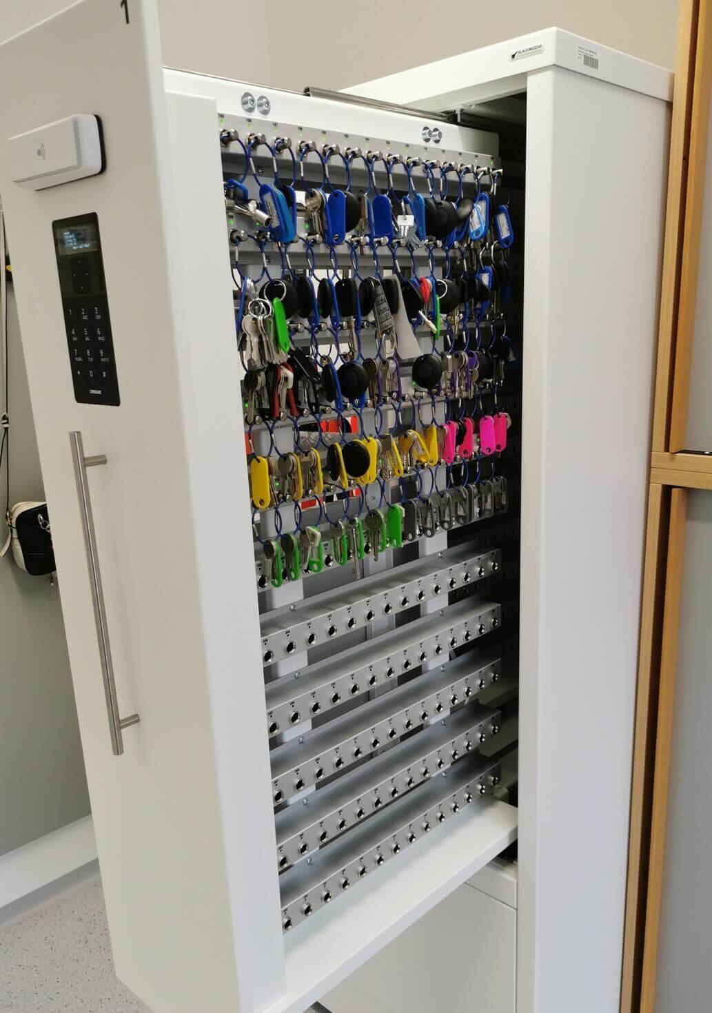 Offener Schlüsselschrank mit elektronischem Zahlenschloss und zahlreichen farbigen Schlüsseln an Haken